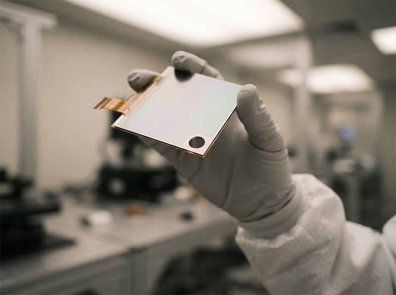 Cleanroom engineer inspecting a laser-cut camera hole on an OLED display panel before final qualification sign-off